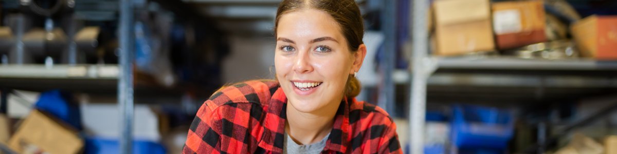 Lächelnde junge Person überprüft Listen im Lager eines Baumarkts