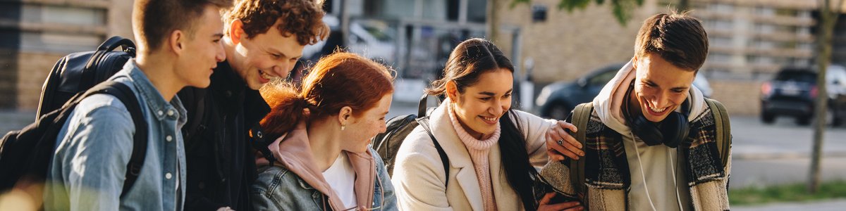 Mehrere jungen Menschen gehen gemeinsam eine Straße entlang und haben Spaß
