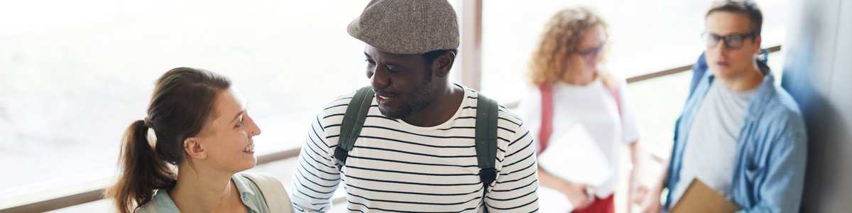 Zwei junge Menschen mit Rucksäcken, die die Treppe hinaufgehen und sich unterhalten