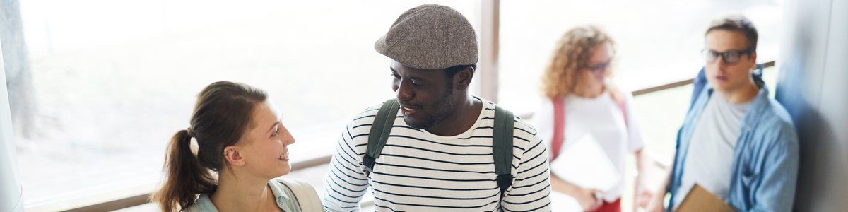 Zwei junge Menschen mit Rucksäcken, die die Treppe hinaufgehen und sich unterhalten