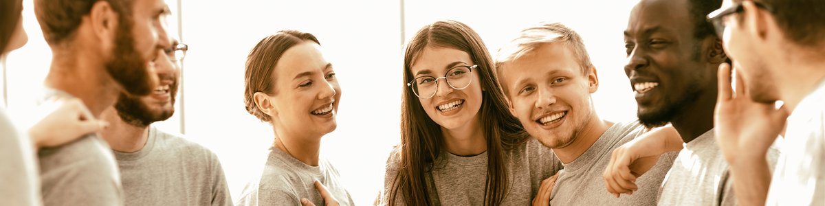 Gruppe fröhlicher junger Menschen, die in einem hellen Raum stehen