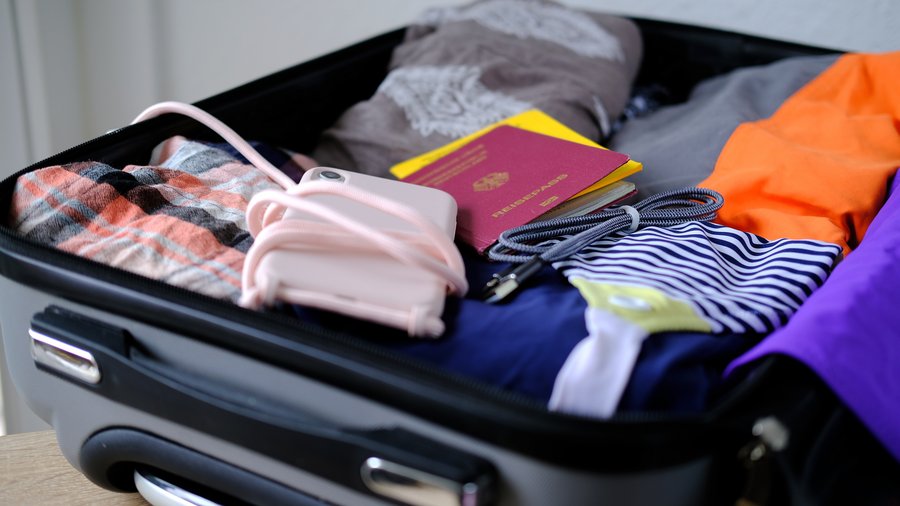 Reisepass, Handy, gefaltete Kleidung in einem offenen silbernen Koffer