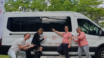Die vier Organisator*innen der Veranstaltung posieren vor dem KiezBus
