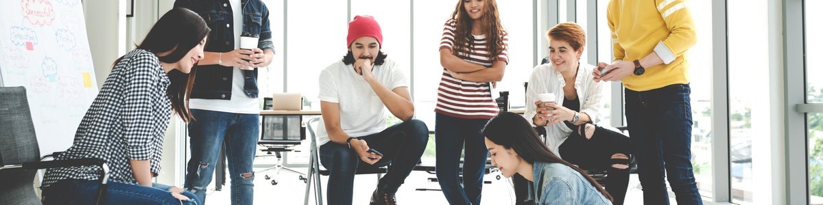 Eine Gruppe junger Menschen trifft sich, betrachtet einen auf dem Boden ausgebreiteten Plan und diskutiert oder brainstormt mit Hilfe von Haftnotizen