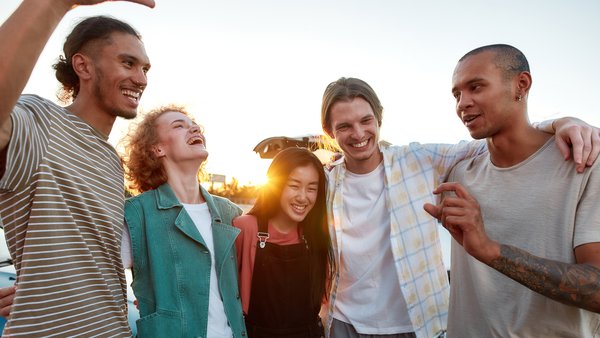 Eine Gruppe junger Menschen umarmen, verbringen gemeinsam ihre Zeit im Freien, lachen und lächeln