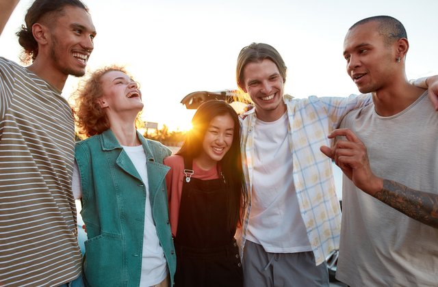Eine Gruppe junger Menschen umarmen, verbringen gemeinsam ihre Zeit im Freien, lachen und lächeln