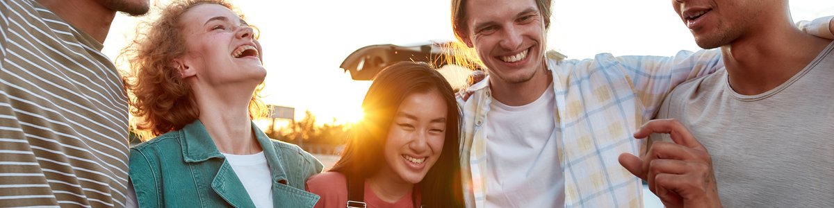 Eine Gruppe junger Menschen umarmen, verbringen gemeinsam ihre Zeit im Freien, lachen und lächeln