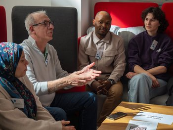 Vier Personen sitzen zusammen. Eine Person spricht. 