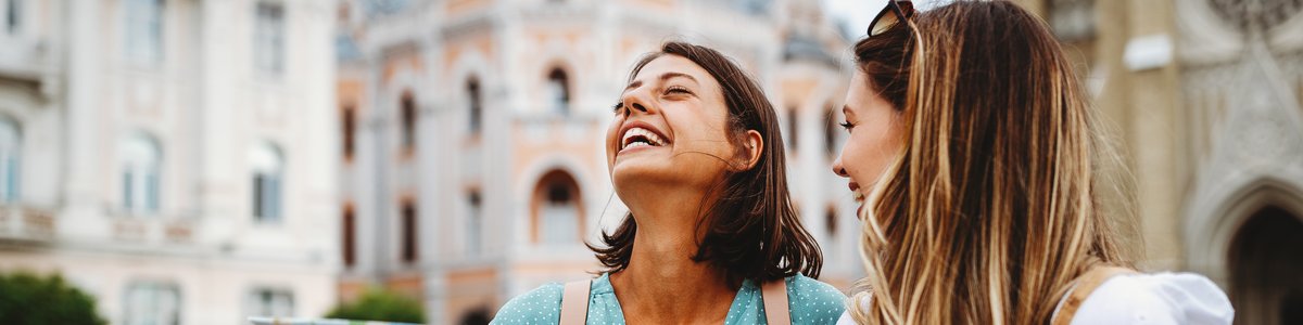 Zwei fröhliche junge Menschen suchen auf einer Karte nach Orientierung in einer Stadt.