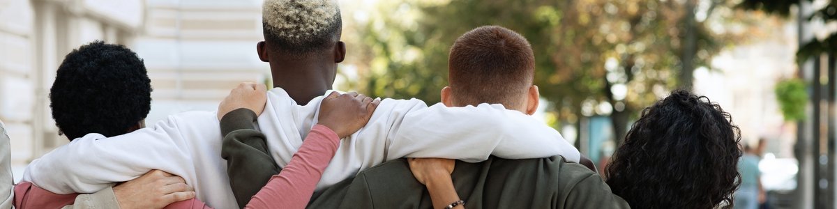 Rückansicht von jungen Menschen, die auf der Straße stehen und sich umarmen