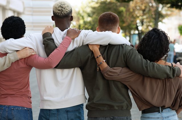 Rückansicht von jungen Menschen, die auf der Straße stehen und sich umarmen