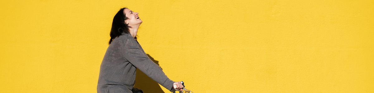 Eine junge Person lacht, während sie auf ihrem Retro-Fahrrad fährt