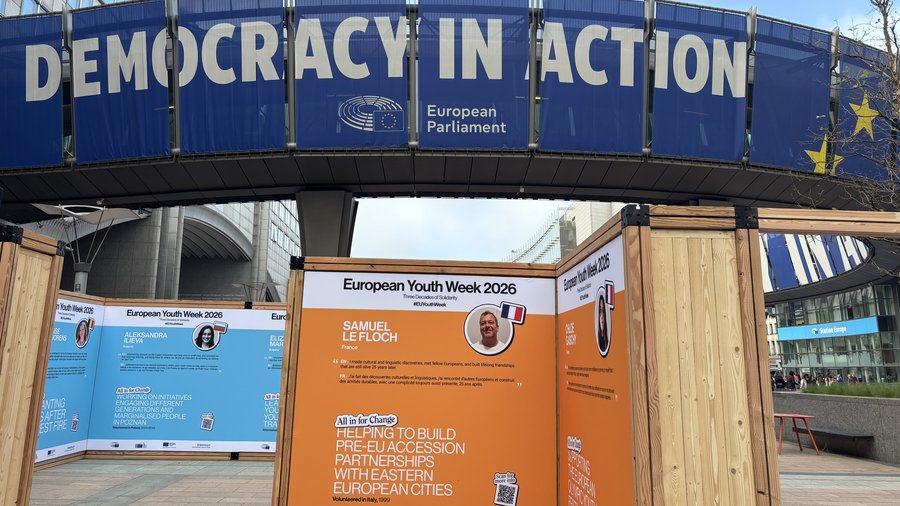 Der Schriftzug "Democracy in Action" ist zu sehen über der Ausstellung vor dem Parlamentsgebäude mit Geschichten von ehemaligen Teilnehmenden des Europäischen Solidaritätskorps.