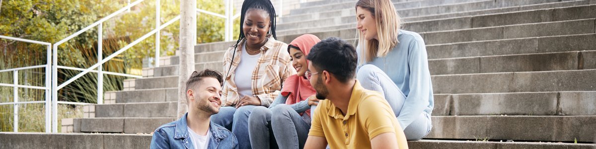 Entspannt sitzen junge Menschen auf Treppenstufen und unterhalten sich