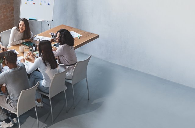 Team, das rund um einen Tisch sitzend diskutiert