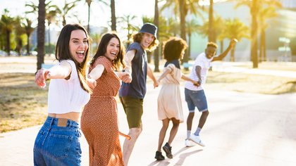 Gruppe junger Menschen, die im Sommer glücklich Hand in Hand laufen