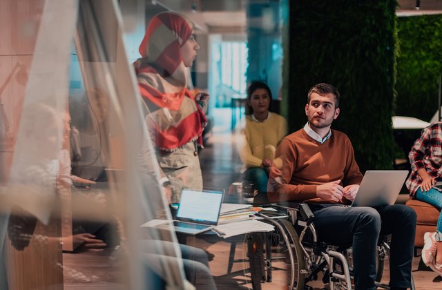 Eine Person hält vor einem vielfältigen Team ein Präsentation