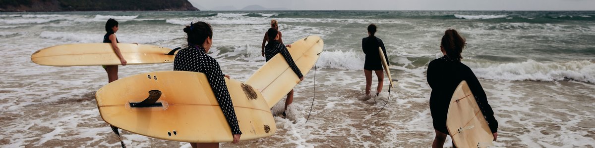 Mehrere Personen mit Surfbrettern kommen ans Meer
