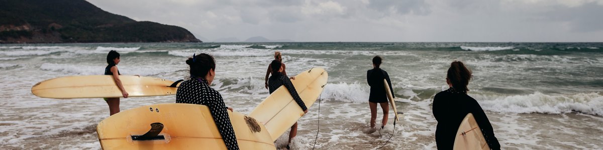 Mehrere Personen mit Surfbrettern kommen ans Meer