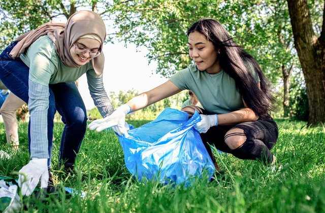Gruppe von Freiwilligen mit Müllsäcken reinigt Stadtpark
